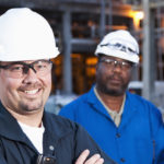 Multi-ethnic group of engineers working at a chemical plant. Focus on man (30s) in foreground.
